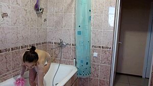 A girl with big tits and a shaved pussy washes under the shower