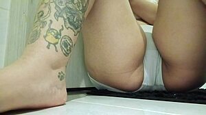 This tattooed milf touches her shaved pussy in the office bathroom