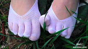 the goddess spreads her cute feet in white socks and jeans on spring grass
