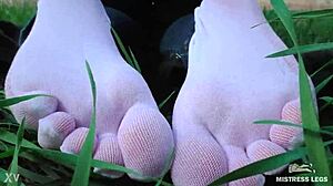 the goddess spreads her cute feet in white socks and jeans on spring grass