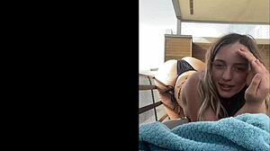 The blonde young woman in bikini strolls along the beach enjoying the warm sun