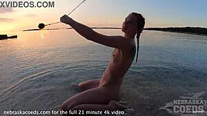 Søt europeisk jente utfører naken ilddans på strand ved solnedgang