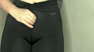 Hun teaser med nærbilde av cameltoe i stramme svarte leggings.